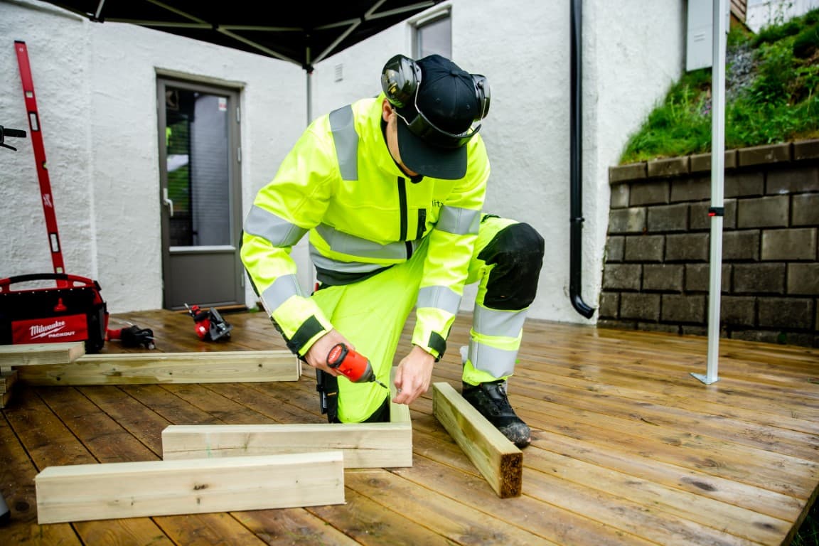 Ability technician in protective workwear assembling with a drill