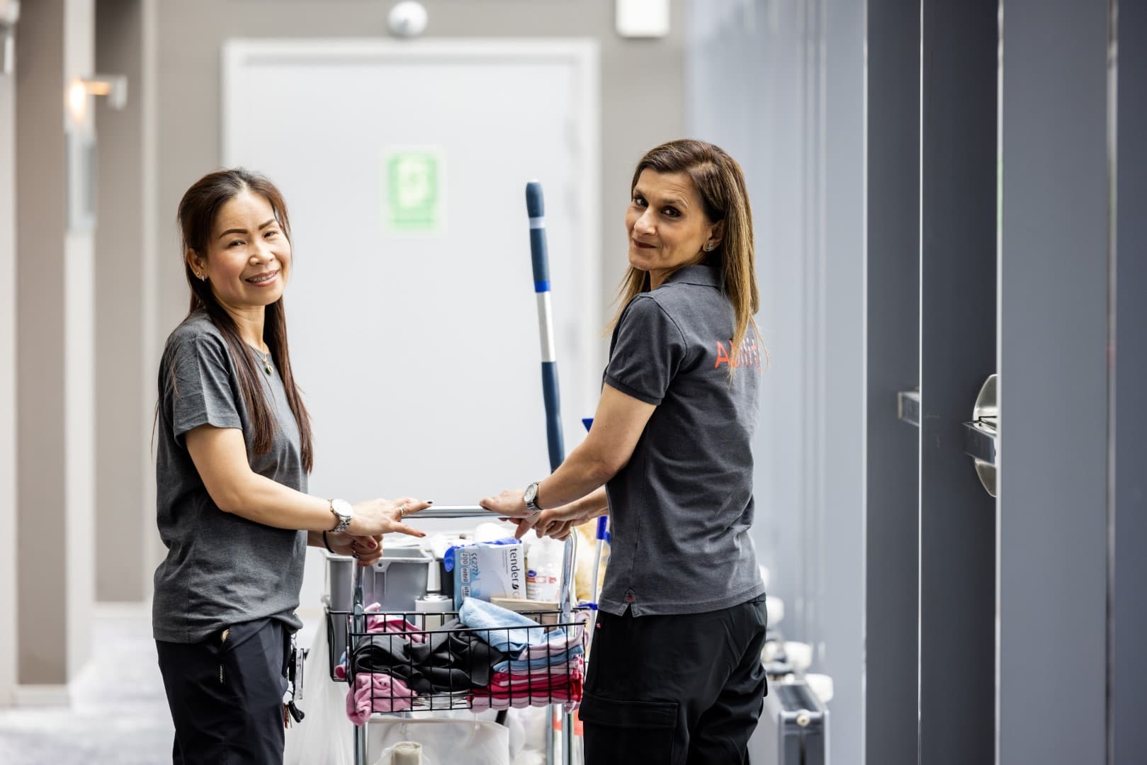 To renholdere fra Ability med housekeeping-tralle i hotellkorridor